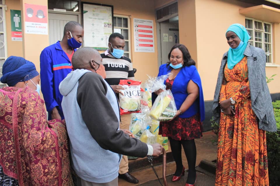 CMC Marketing Coordinator, Imelda Kabera hands over a package of food items to a diabled Muslim in Nakawa division