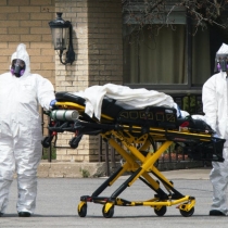 Workers wearing protective gear remove bodies of people who have died from COVID-19 from a New Jersey nursing home morgue