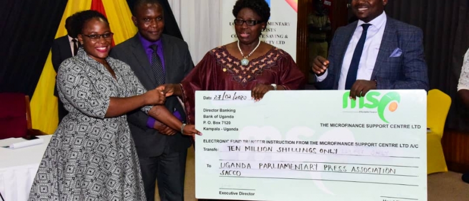 Speaker Kadaga hands over a dummy cheque of Shs10m to UPPA SACCO chairperson Suzan Nawonga (L) as Minister Haruna Kasolo looks on