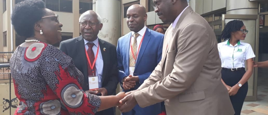 Minister Karooro Okurut (L) is welcomed by KIU leadership