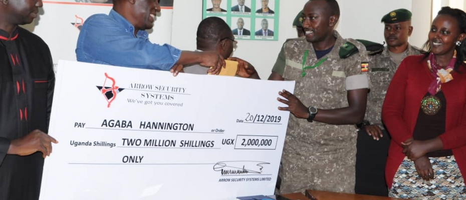 Mike Mukula (in blue) Chairman Arrow Security Systems hands over a dummy cheque to Corporal Hannington Agaba (UWA Ranger). Courtesy photo