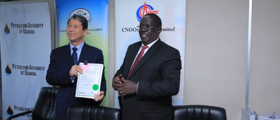 Zhao Shunqiang, the President, CNOOC Uganda Limited receives the certifcate from Tom Okurut (R), NEMA ED