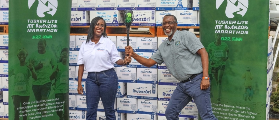 Pearl Nimusiima, the Public Affairs and Communications Manager of CCBU shakes hands with Amos Wekesa, the Tusker Lite Mt.Rwenzori Marathon  Team Leader  as she hands over a dummy cheque worth UGX 173m and boxes of Rwenzori  Pure Natural Mineral Water ahead of the Marathon