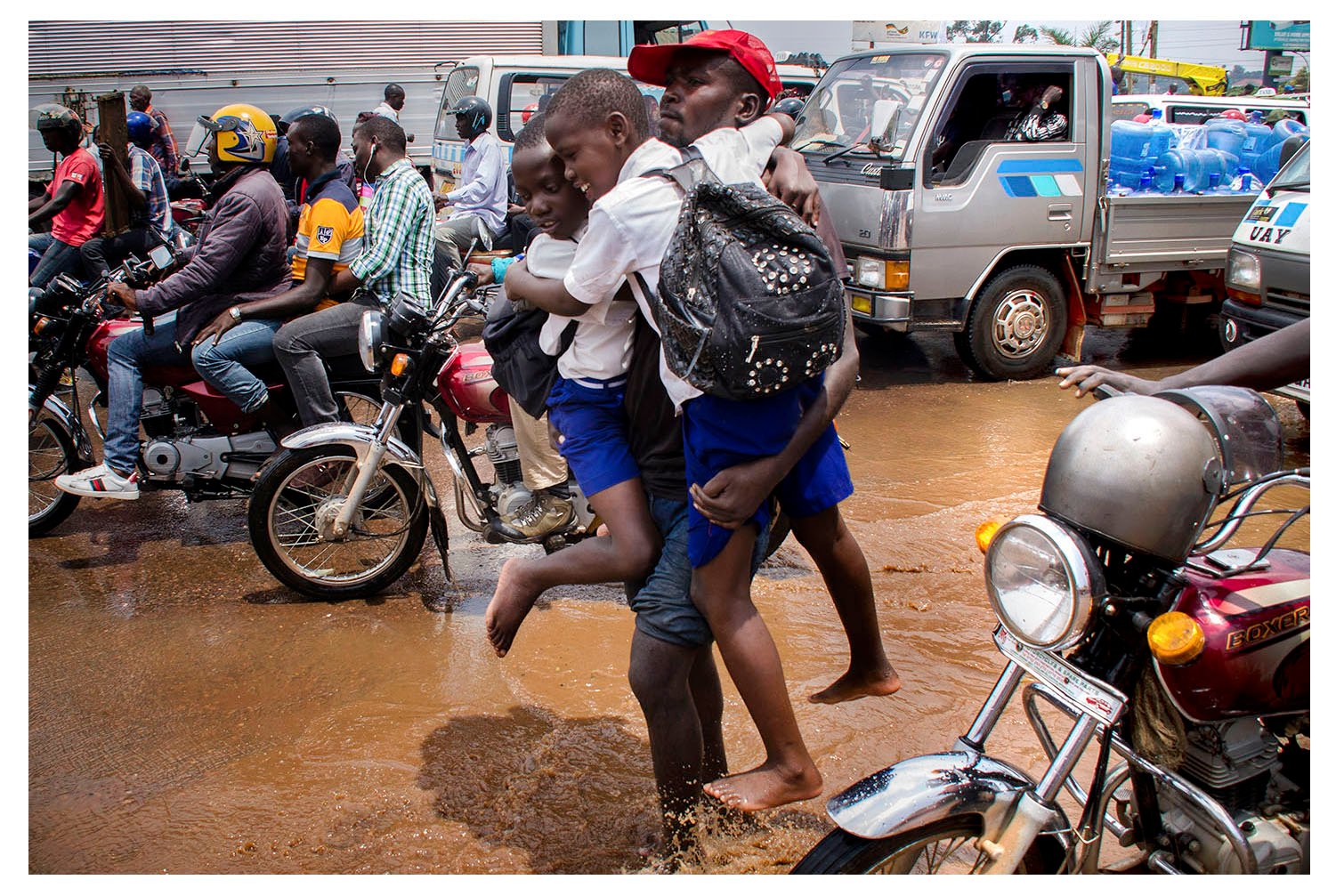 Call him Mr. Hero. He helps students at flooding clocktower in Kampala to cross over during rains for free (Badru Katumba)
