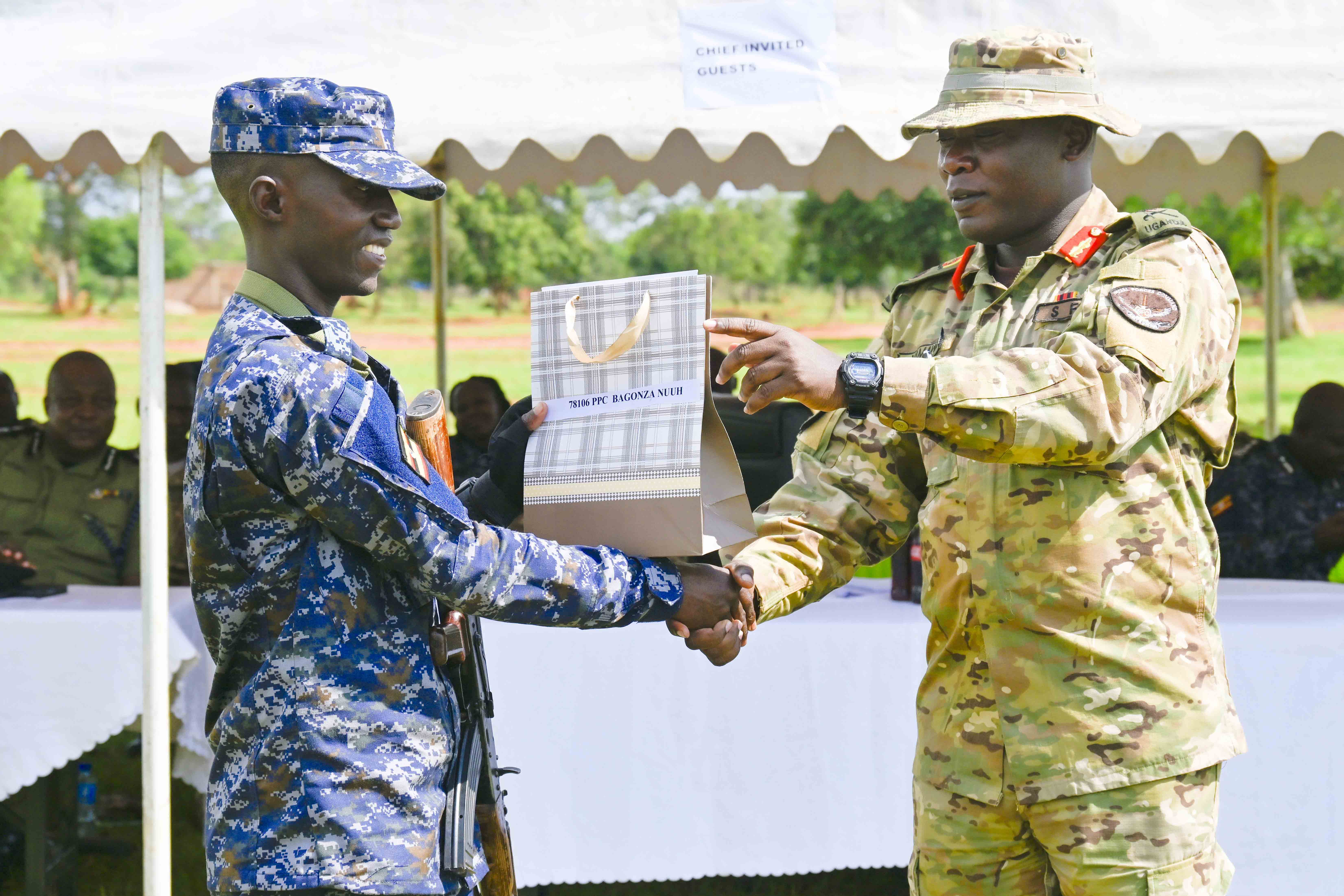 The Chief Guest Chief Of Staff Special Force Command Brig. Gen. Paul Namawa (right) hands over a gift to the Best Overall Trainee PPC Bagonza Nuuh (left) during the Passing out of PPG Trainees at the Police Presidential Guard  Special Force Training School Fort Samora Machel in Kaweweta on the 22nd October 2024.
